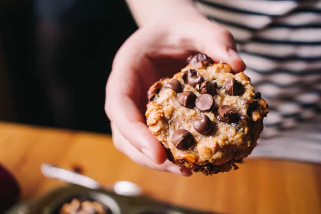 hand holding up a banana nut and oat breakfast muffin with chocolate chips