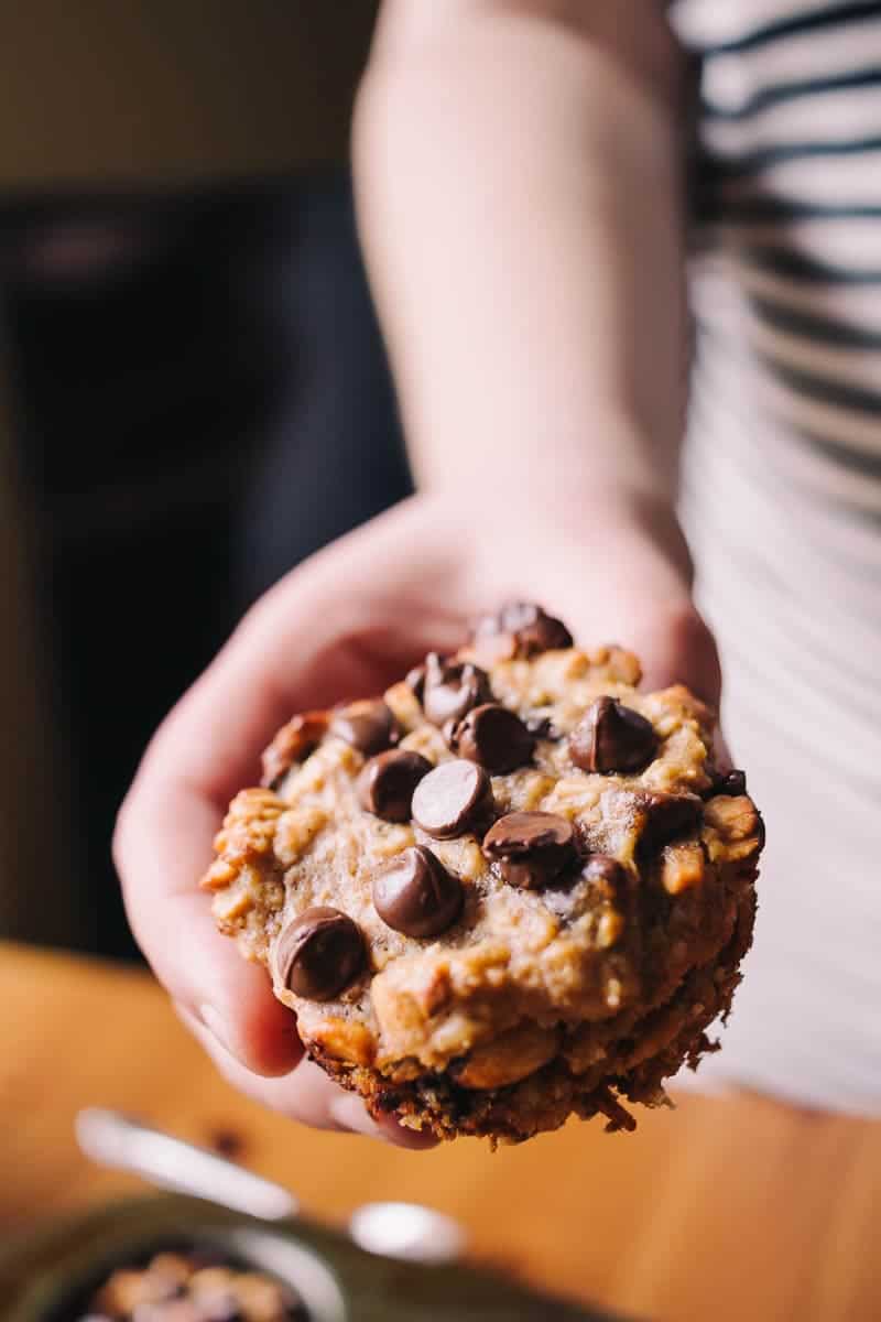hand holding a muffin to the screen with chocolate chips