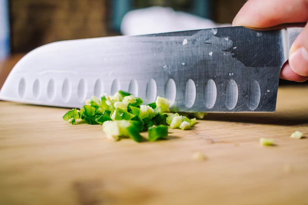 close up of a knife chopping jalapenos