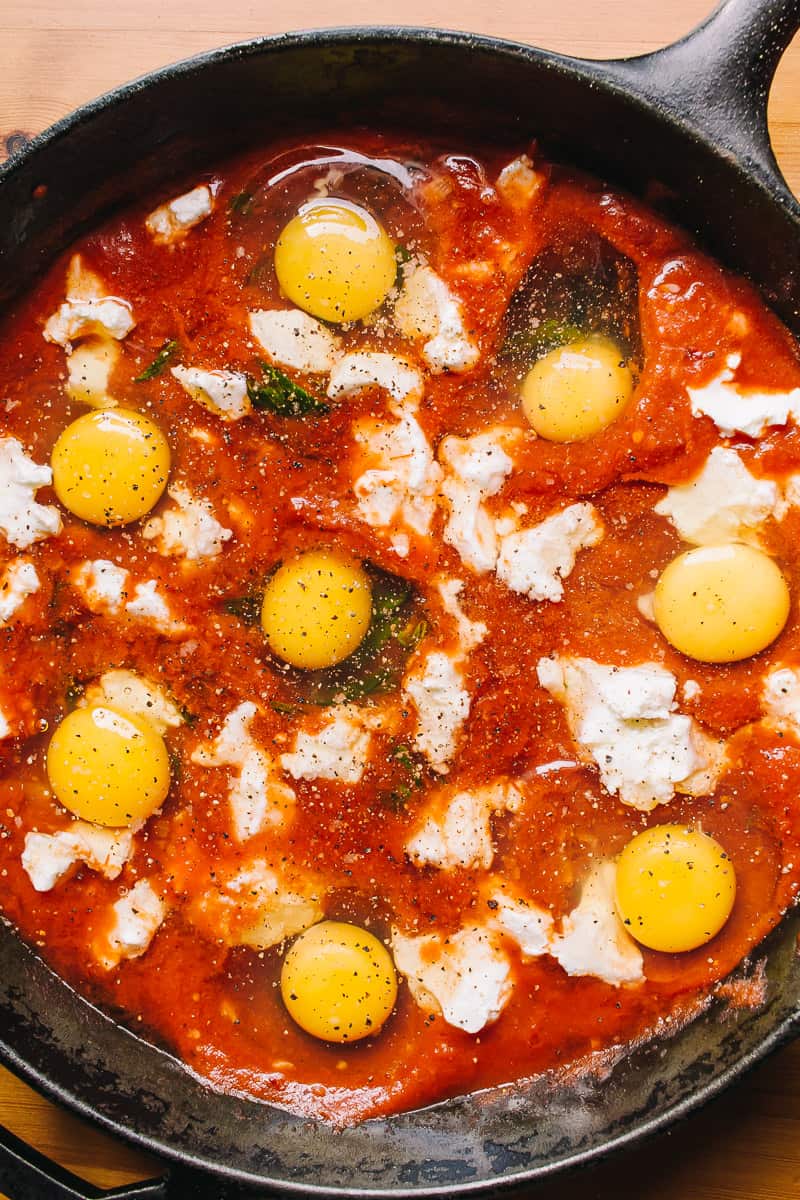 skillet with tomato sauce and eggs with goat cheese