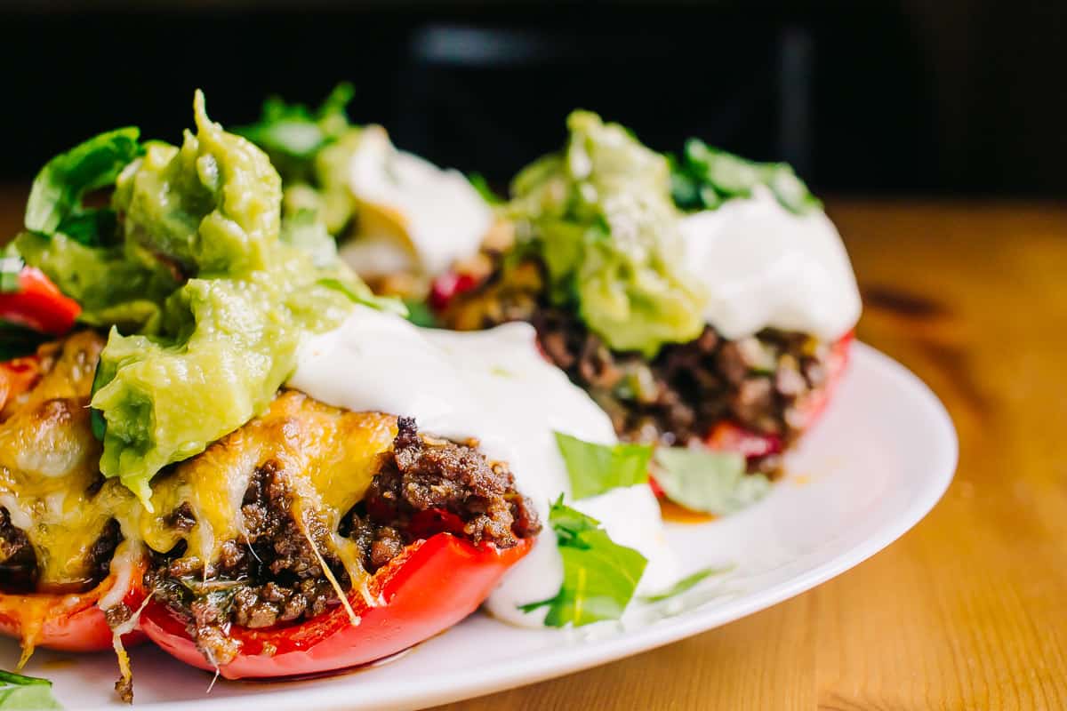 plate of tex mex stuffed bell peppers with sour cream and guacamole
