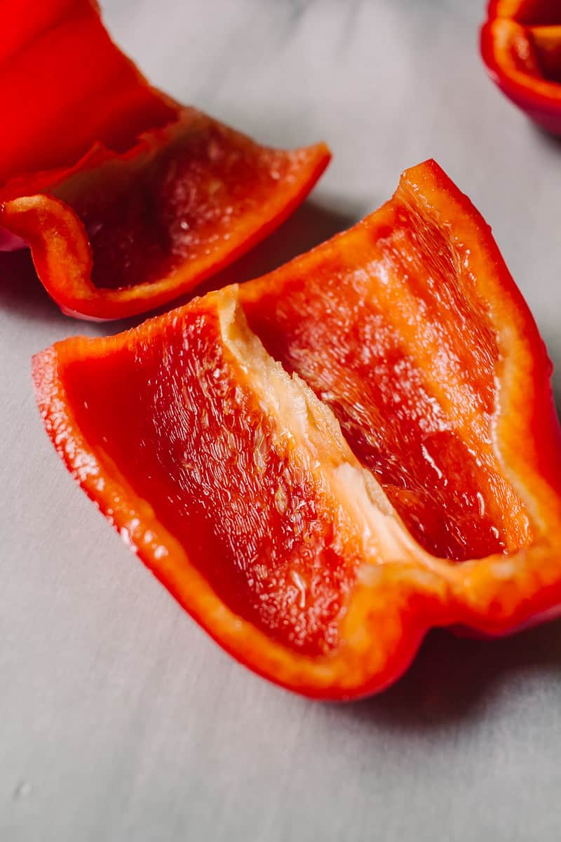 red bell peppers cut in half on parchment paper