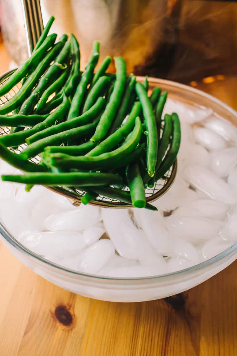 adding cooked green beans to an ice bath