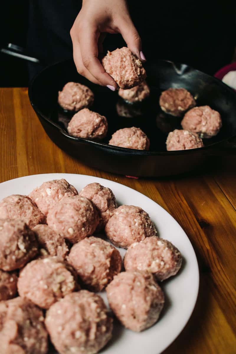 raw lamb meatballs going into a skillet