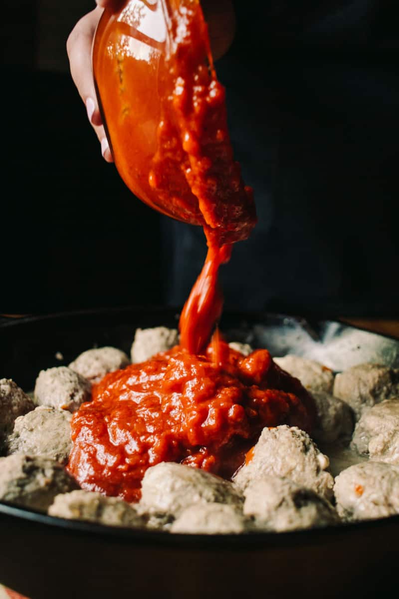 adding tomato sauce to lamb meatballs