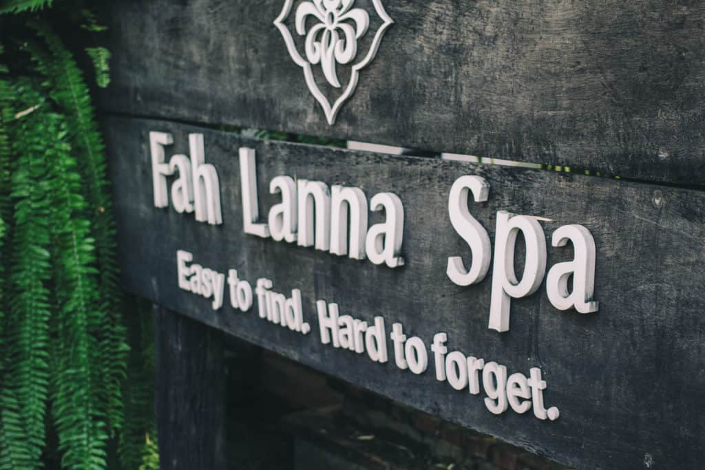 wooden sign with greenery of fah lanna spa with text stating easy to find, hard to forget