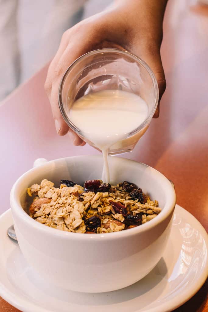 pouring milk into a bowl of homemade granola at caffe arrivadolce