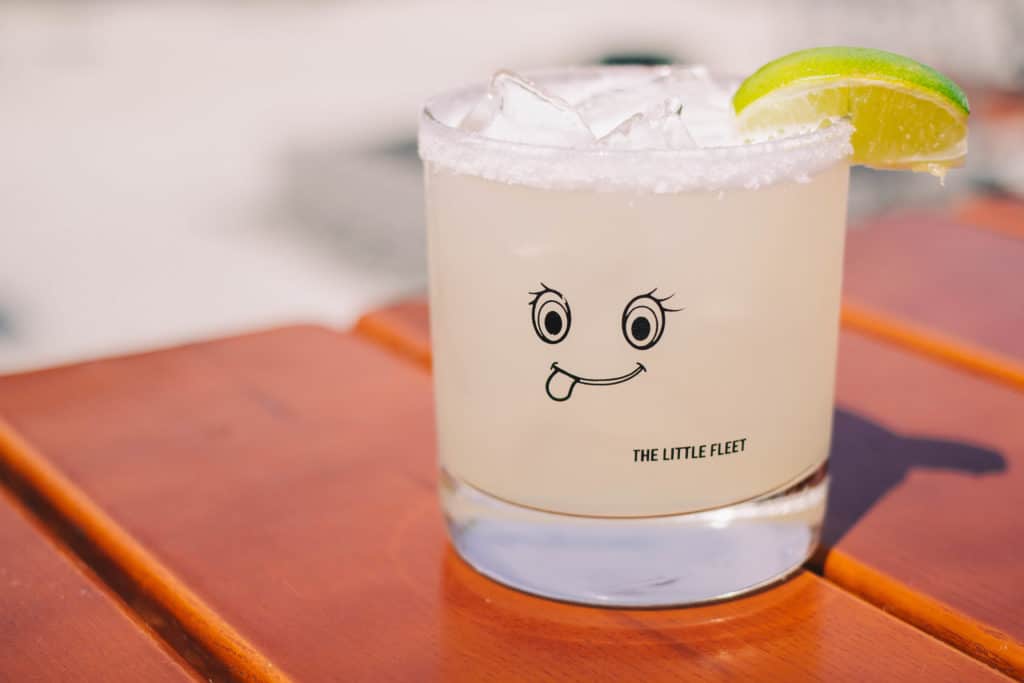 the little fleet signature fresh squeezed margarita with a glass with a face on it 