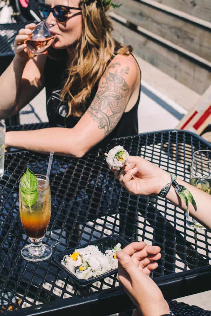 two women eating and drinking outside enjoying sushi