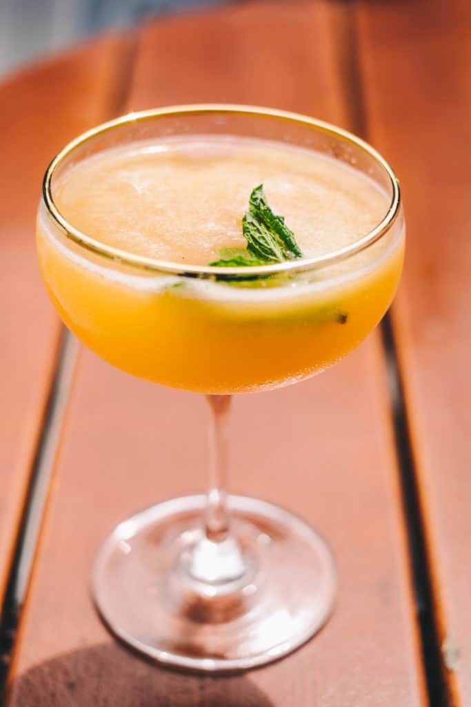 clementine cocktail in a coupe glass with a mint garnish