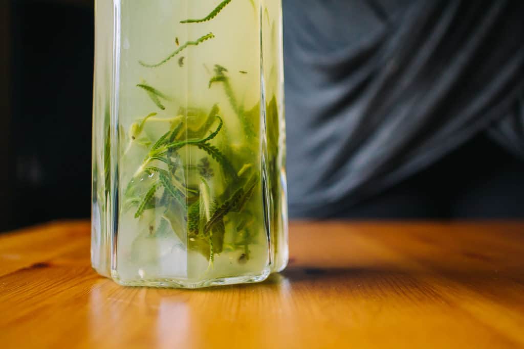 herbs swirling around in a pitcher of freshly made lemonade 