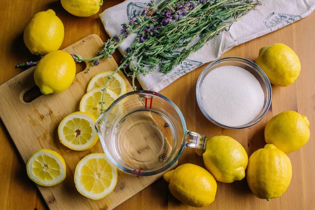 overhead view of ingredients for keto lavender sage lemonade with sage lavender lemons water and sweetener