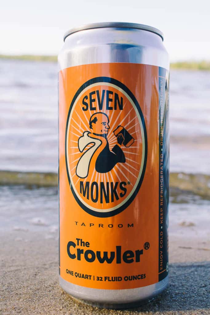 growler of beer in the sand by the water from 7 monks tap room