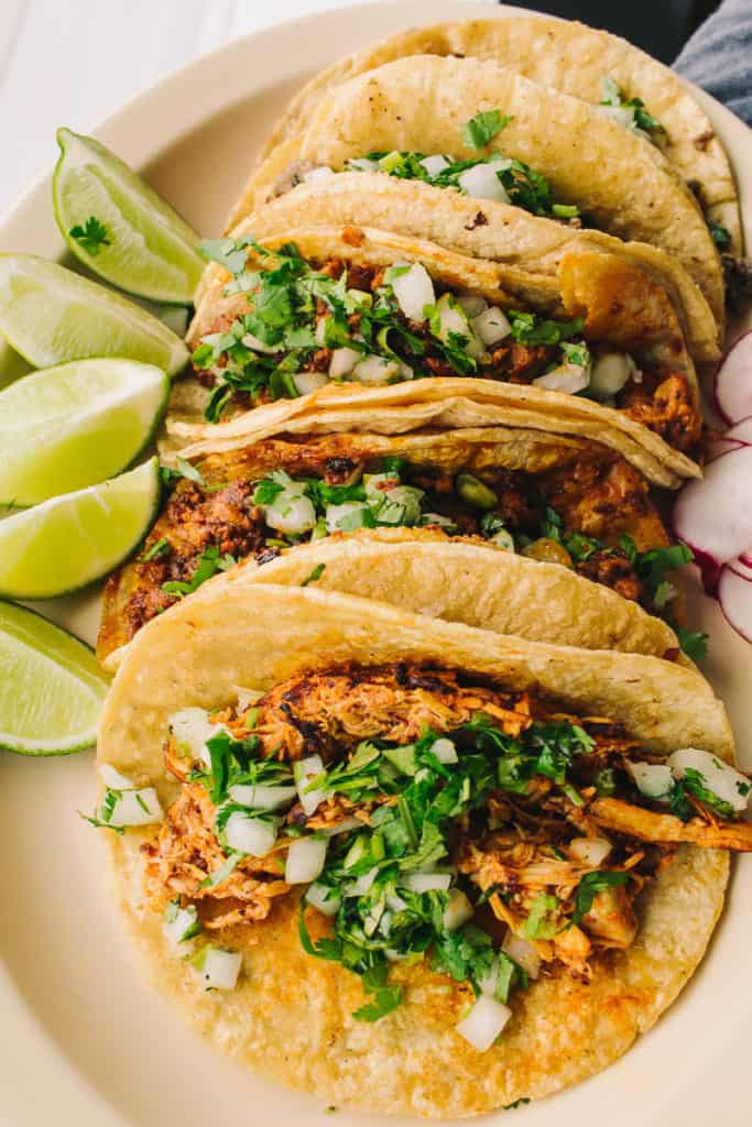 plate of authenthic mexican tacos with lime and cilantro at taqueria tc latino