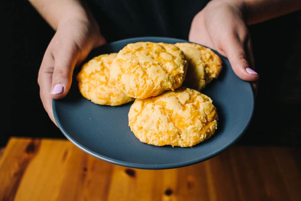 hand on plate full of cheddar biscuits