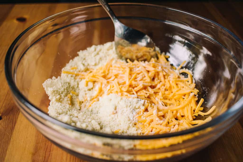 low carb cheddar biscuit mixture in a glass bowl on a light brown wood table