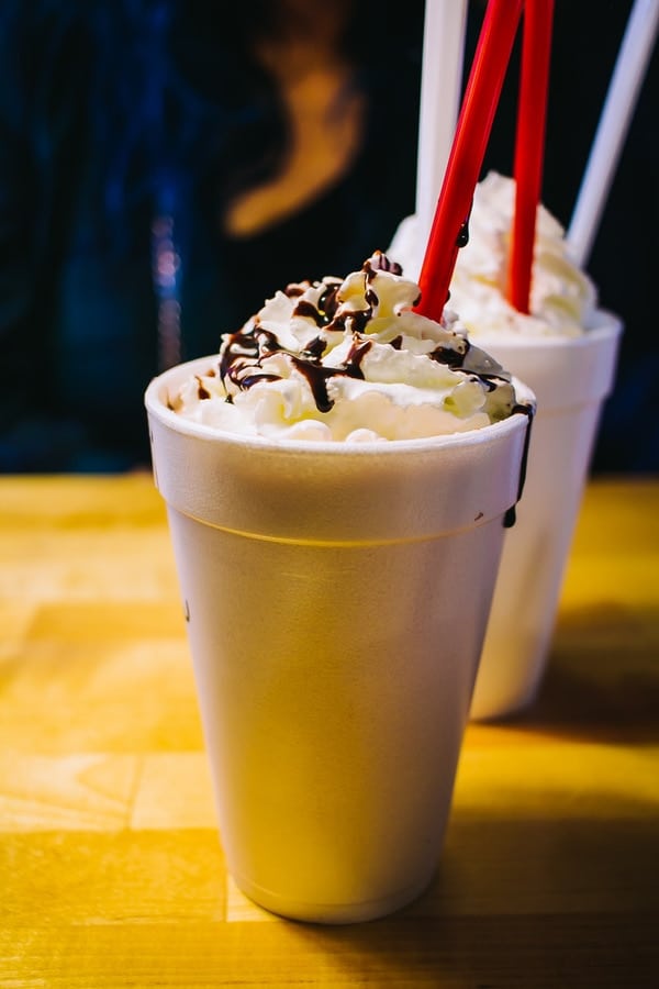 two milkshakes with whipped cream and chocolate drizzle