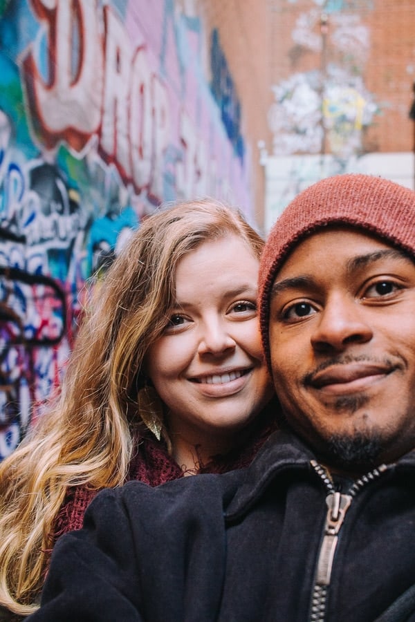 a man and woman smiling together in graffiti alley
