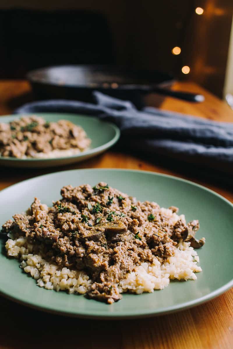 Low Carb Beef Stroganoff on two green plates with a cast iron in the background