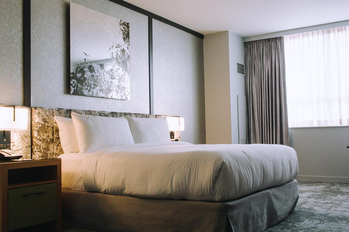 grey hotel room with a white bed and bright windows at the loews chicago o'hare hotel