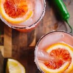 overhead shot of two blood orange cocktails with pink salt and serrano peppers