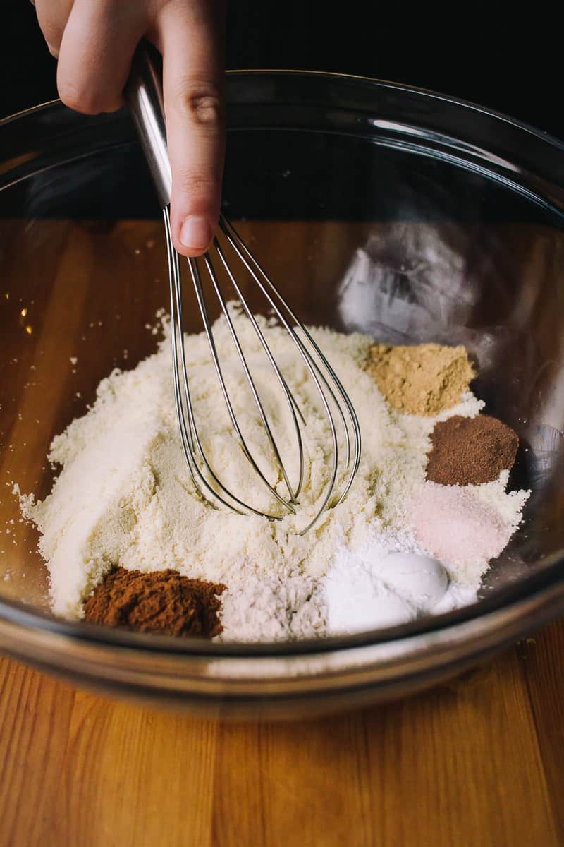 whisking dry ingredients together in a large glass bowl for low carb carrot cake cupcakes