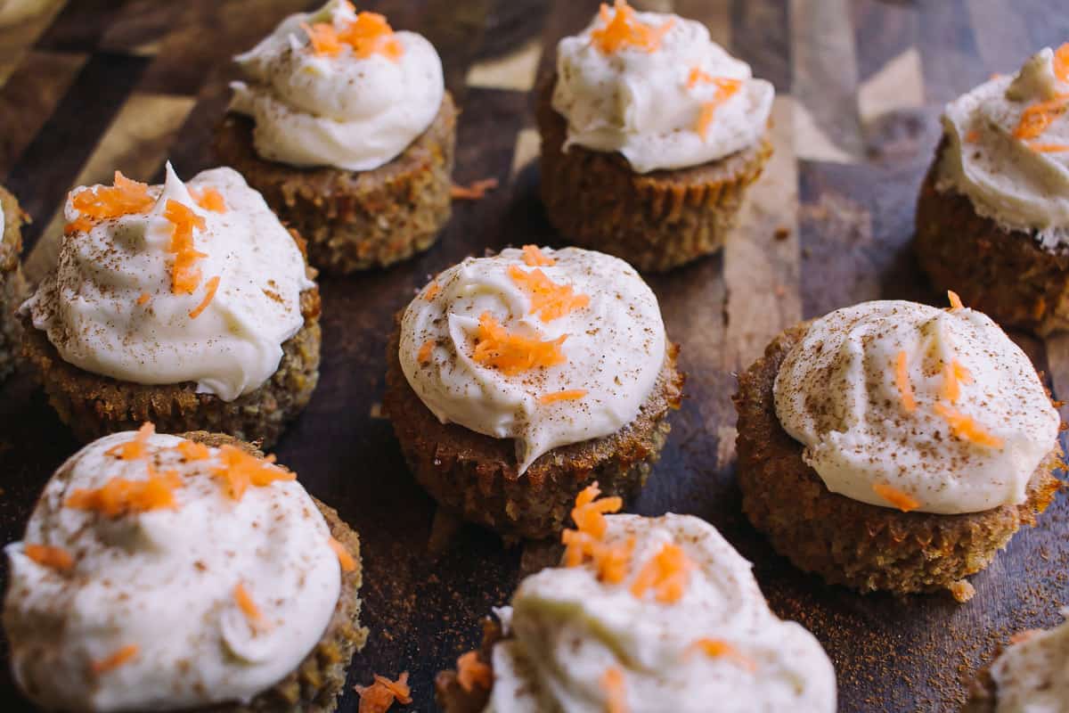 low carb carrot cake cupcakes on a dark wood chopping block