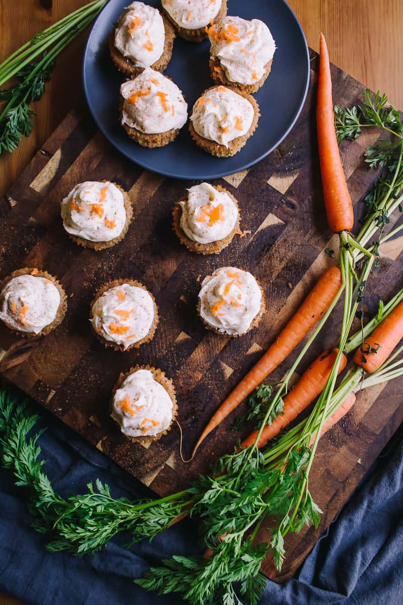 Low Carb Carrot Cake Cupcakes on a cutting board overhead shot with fresh carrots
