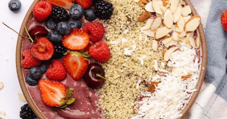 keto acai smoothie bowl with fruit toppings, hemp hearts and coconut flakes