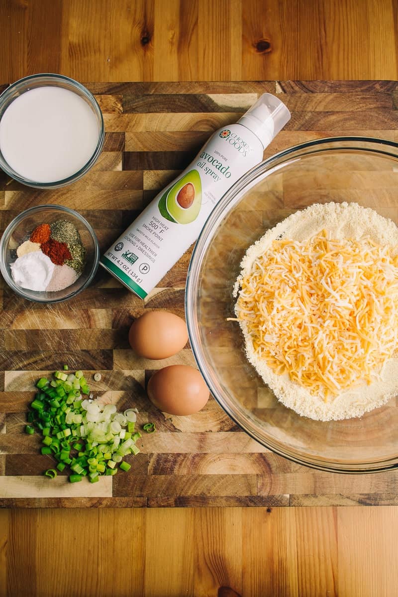 overhead view of chopped green onions, eggs, shredded cheese, spices, milk oil and almond flour