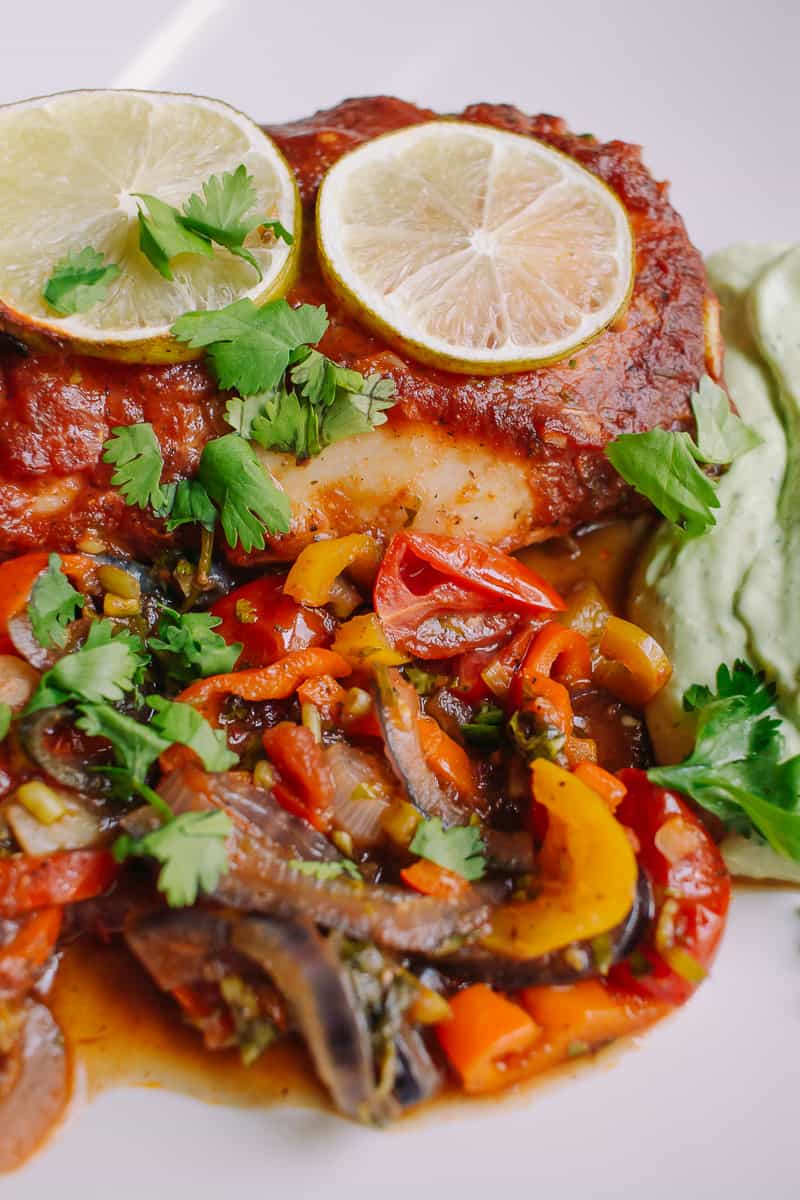 up close with a plate of Spicy Baked Cod with Lime and Rainbow Vegetables and a side of avocado lime crema