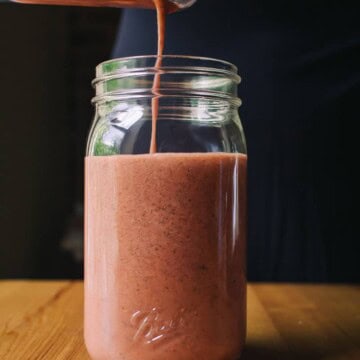 hand pouring Sugar Free Raspberry Basil Vinaigrette into a mason jar