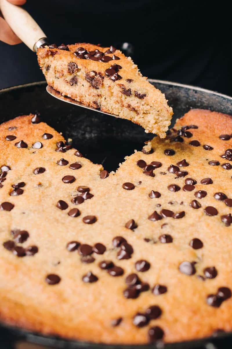 Low Carb Chocolate Chip Banana Bread Skillet with one piece being lifted from a cast iron skillet