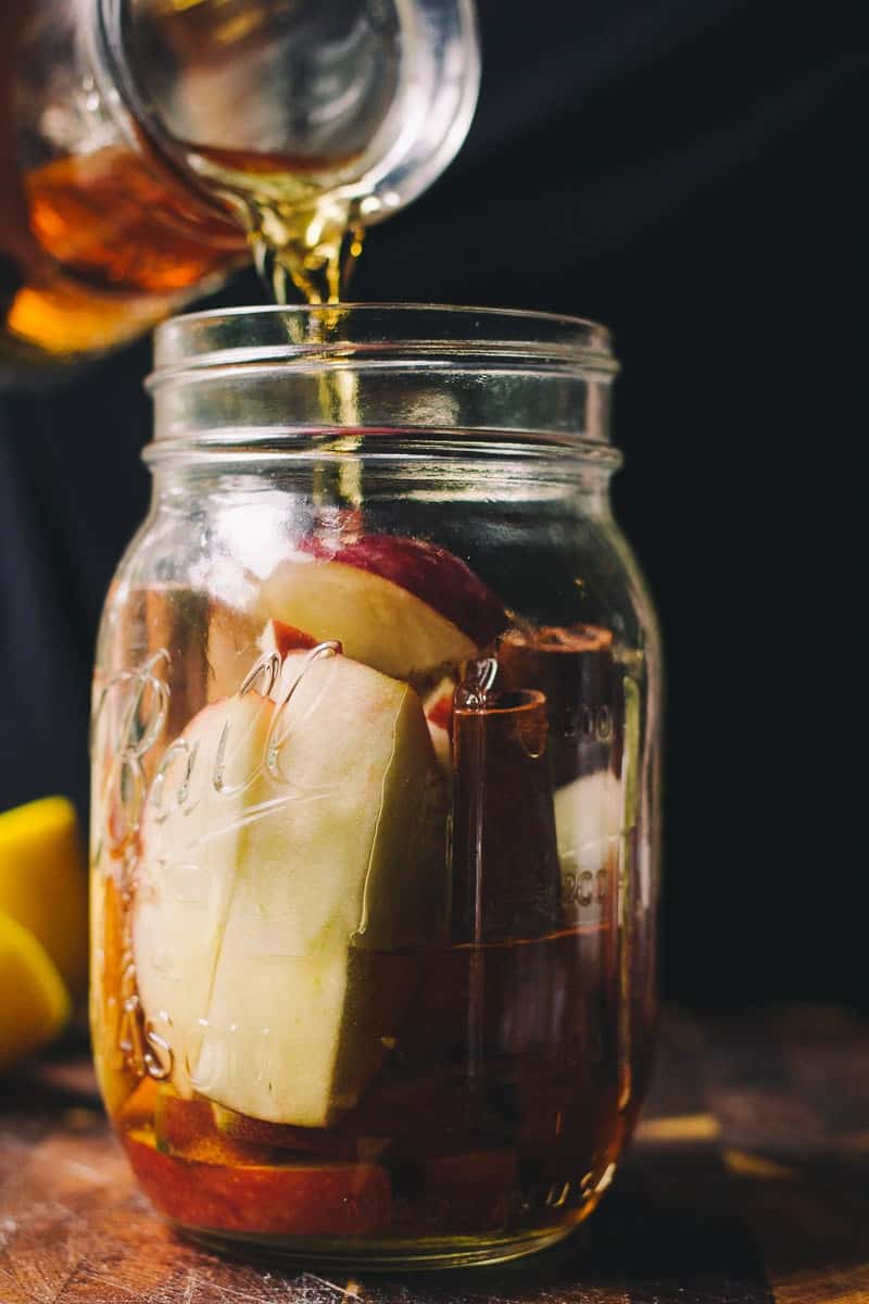 infusing whiskey with apple and cinnamon in a mason jar. 