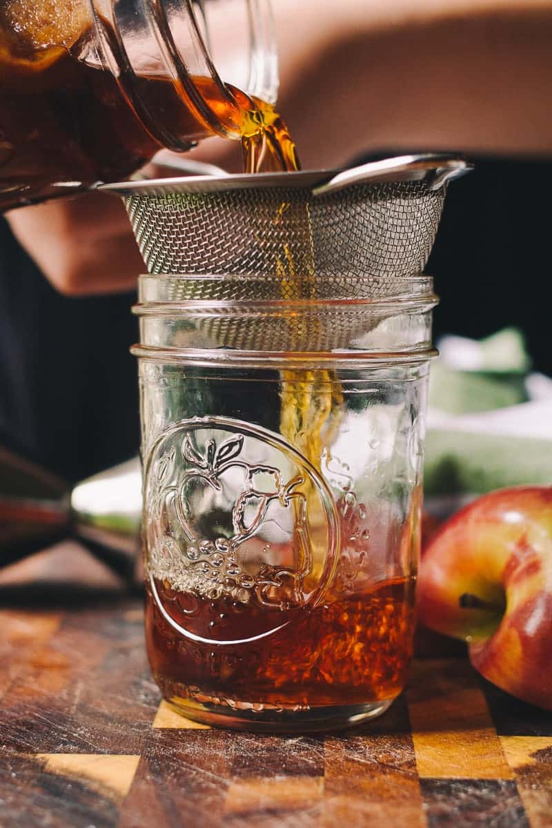 straing whiskey into a clean jar to make apple cinnamon whiskey. 