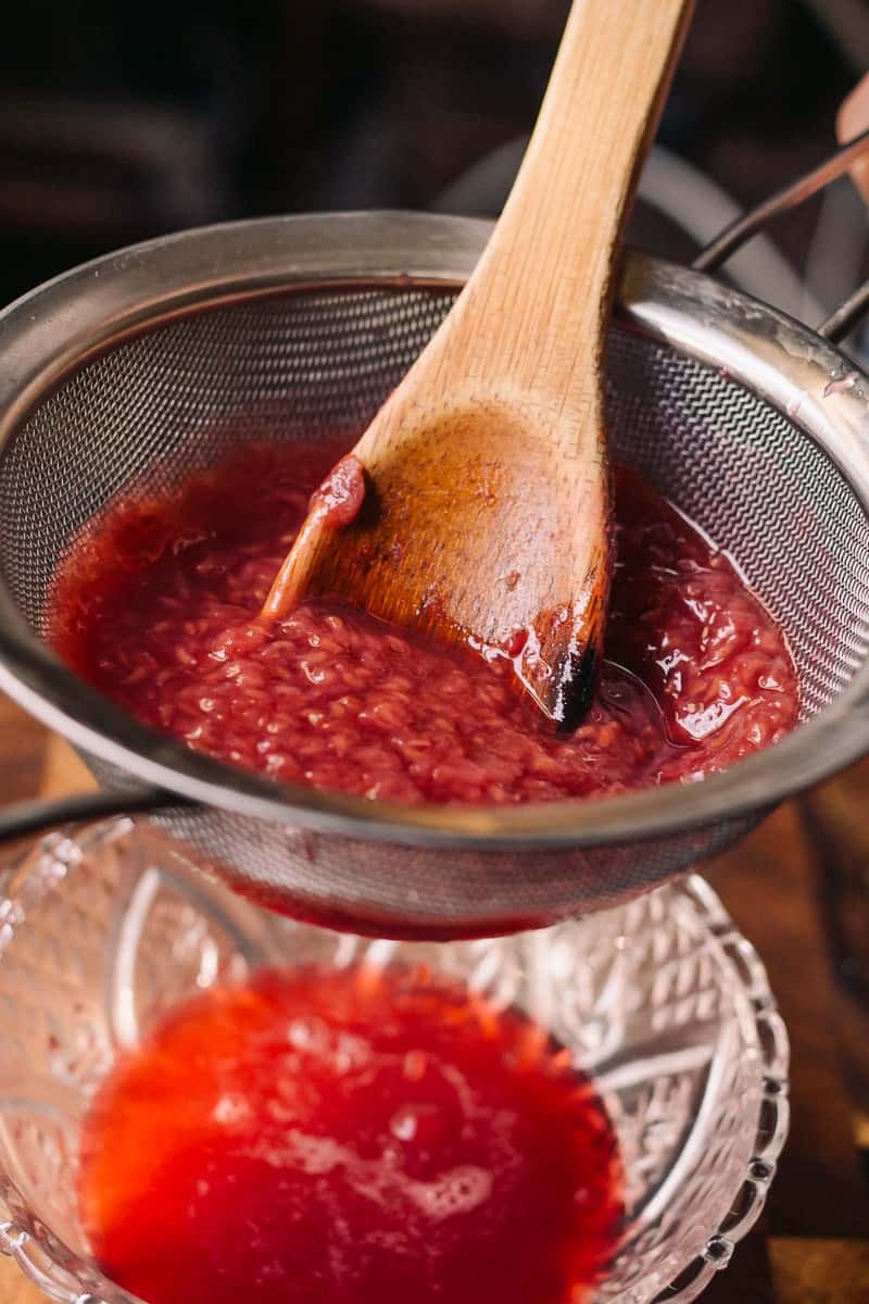 separating raspberry jam from seed with metal strainer and glass bowl