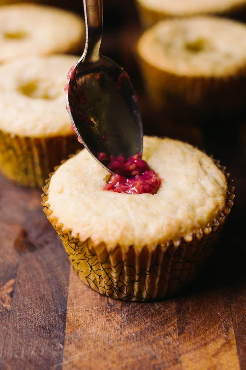 vanilla cupcake being filled with raspberry jam