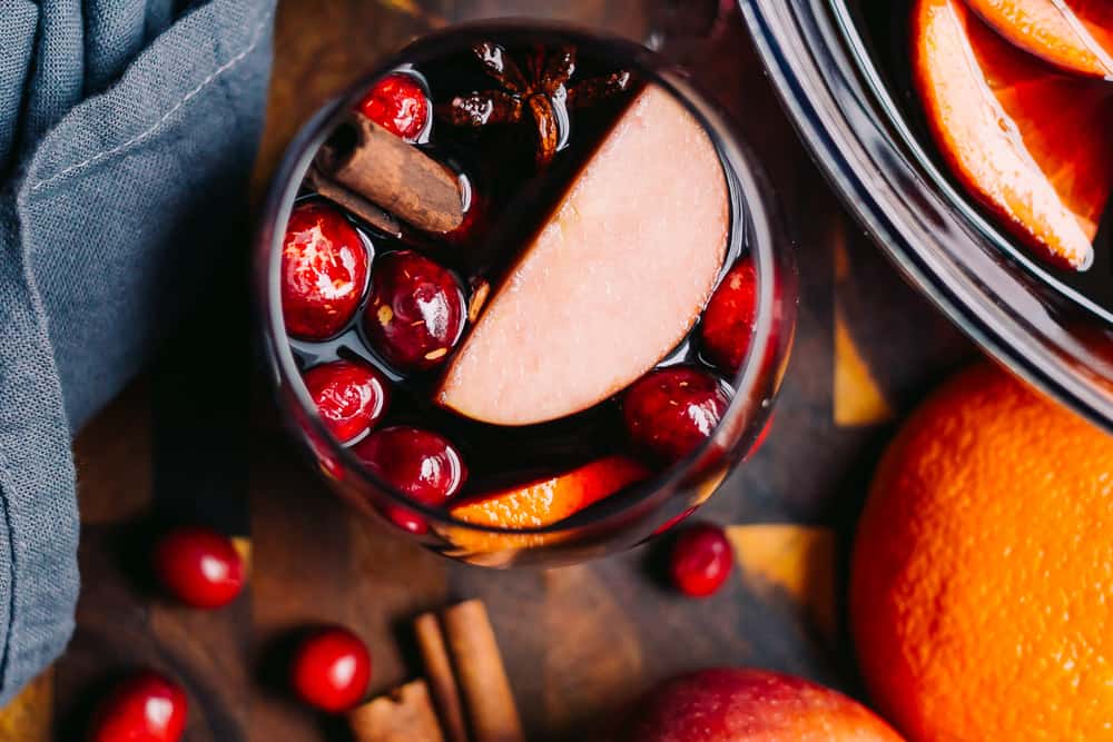 glass of sangria with cranberries apples and cinnamon