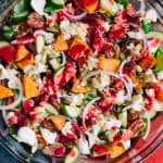 Harvest Salad with Cranberry Lemon Vinaigrette in a glass bowl with a grey blue towel