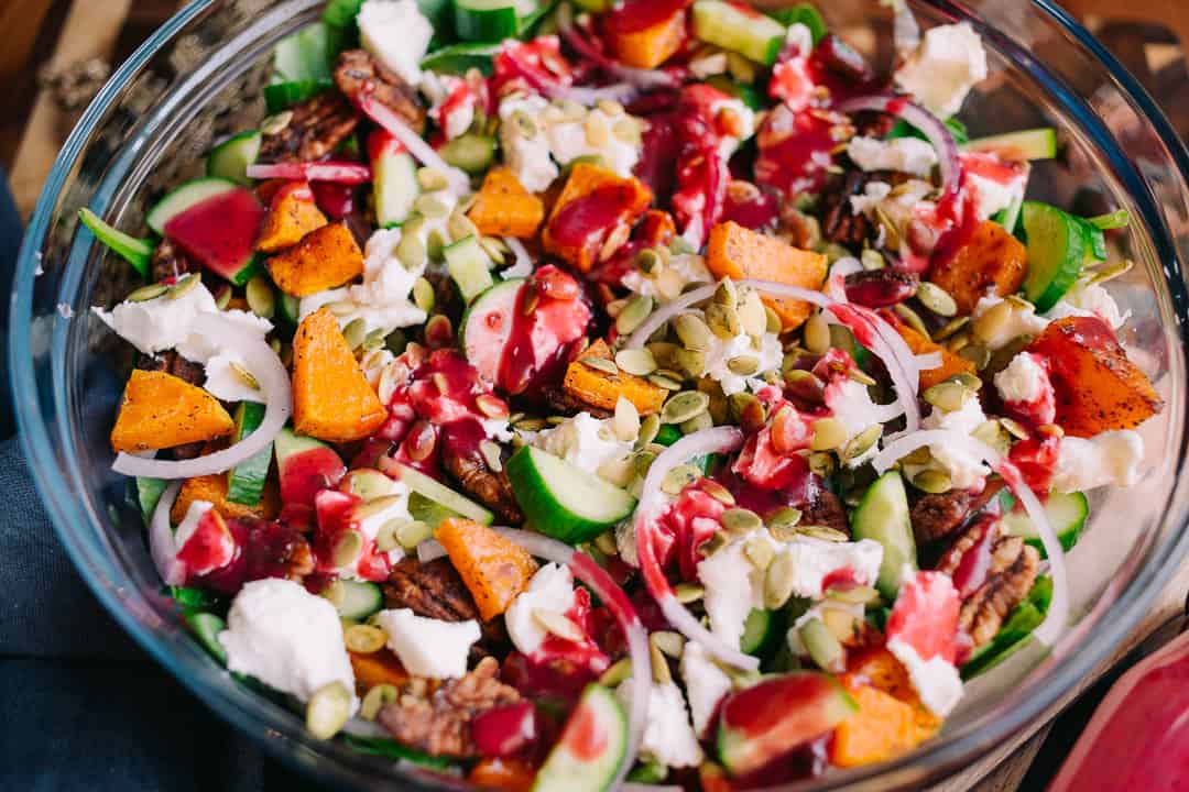 colorful salad with cucumbers butternut squash pepitas goat cheese and cranberry dressing