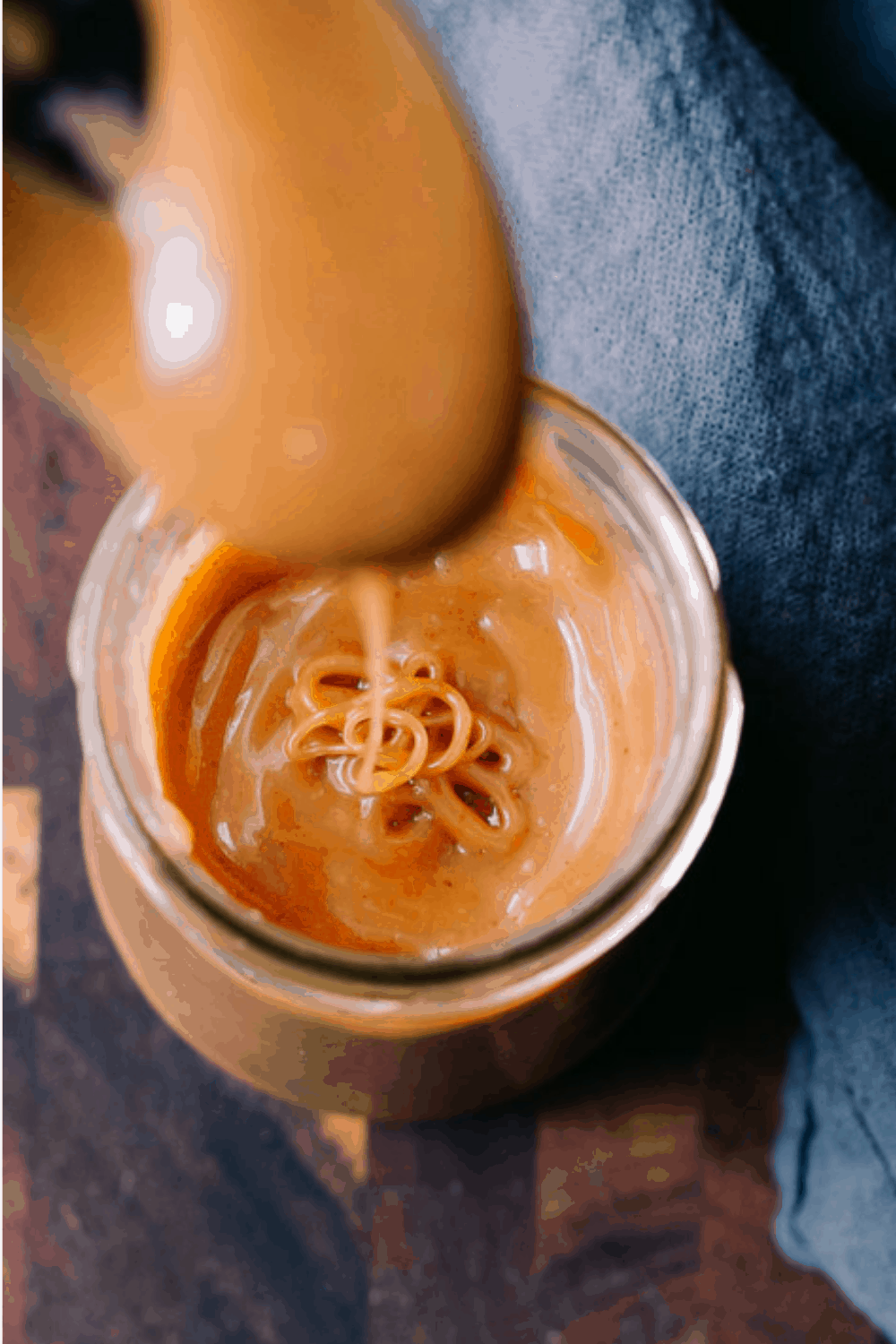 closeup shot of keto salted caramel sauce in a jar dripping from a spoon