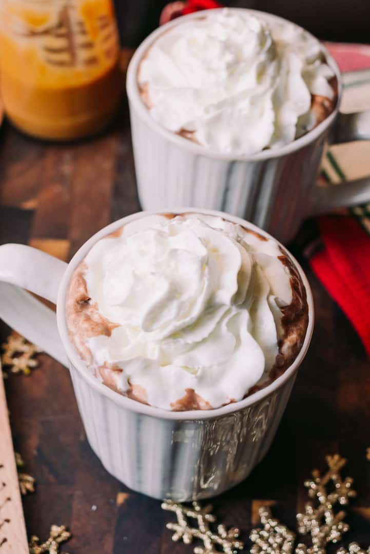 two mugs of low carb hot cocoa topped with whipped cream in mugs