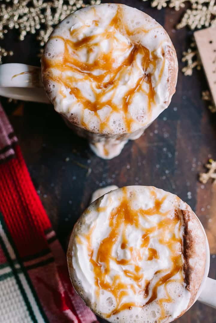 overhead of two hot cocoa mugs with caramel drizzle
