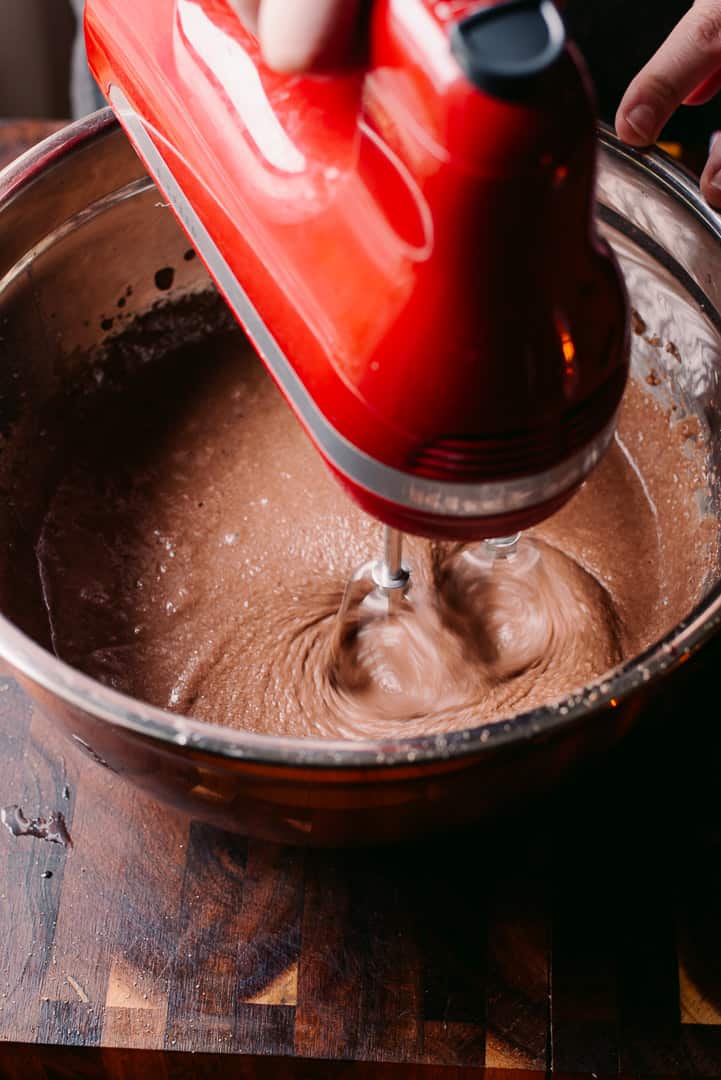 mixing chocolate cake batter with a red hand mixer