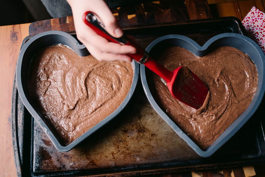 smoothing chocolate cake batter into two heart shaped silicone cake molds for a low carb valentine's day cake