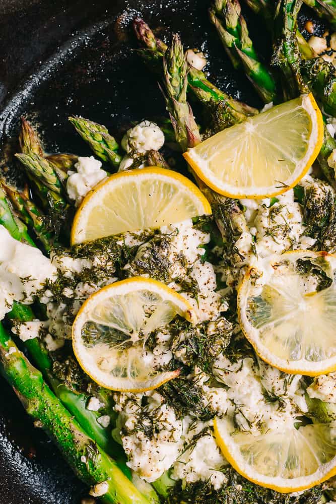 baked asparagus in a cast iron skillet with lemons, goat cheese and dill