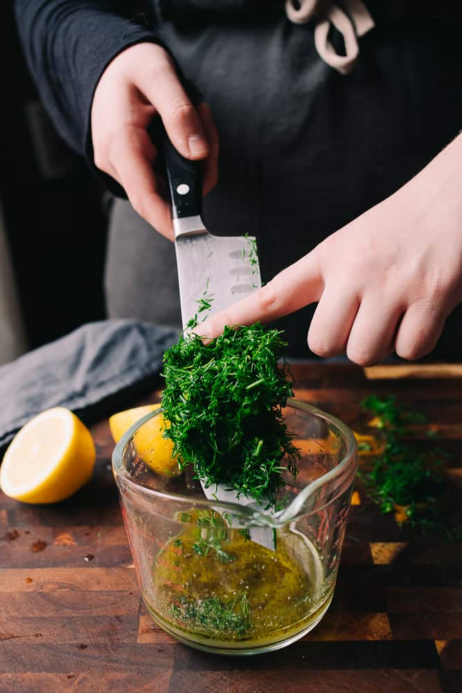 fresh dill sliding off a knife into a measuring cup