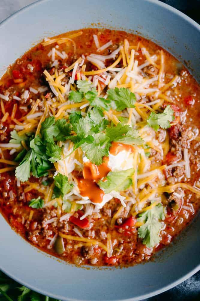 bowl of beanless chili with cilantro sour cream and cheese