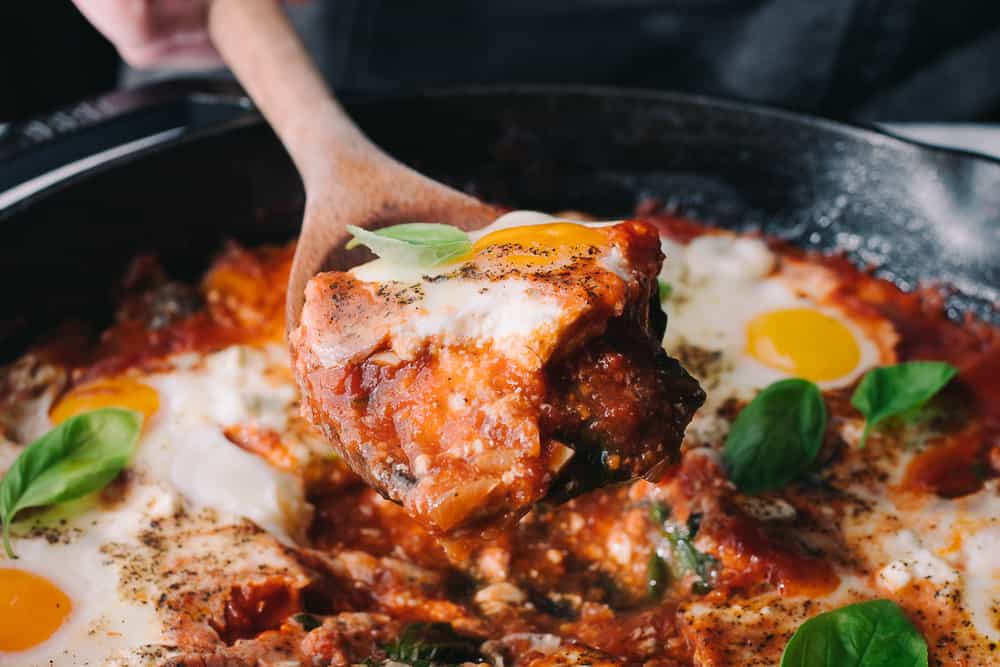 wooden spoonful of shakshuka with goat cheese and basil