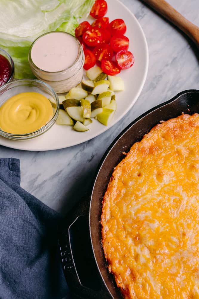 flatlay of cheeseburger casserole skillet with cheeseburger toppings